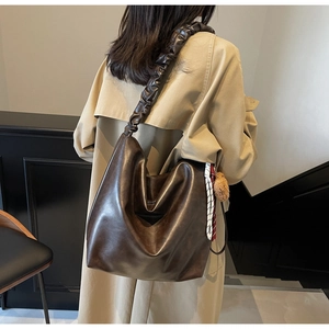 Detail of brown leather bucket bag with scrunchie shoulder strap and checkered scarf
