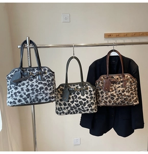 Trois sacs cabas en fausse fourrure léopard gris, vert et marron suspendus sur un portant