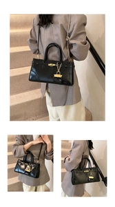 Detail einer schwarzen Lackleder-Handtasche mit goldenem Schloss und Kettenanhänger