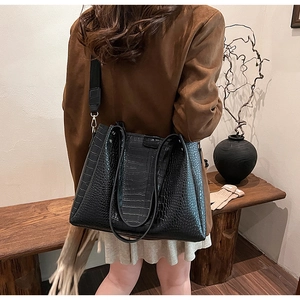 Detailed view of the black crocodile embossed tote bag texture with wide shoulder strap