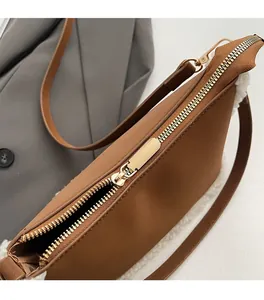 Detailed macro view of the gold metal zipper and white faux fur trim on a brown leather bag
