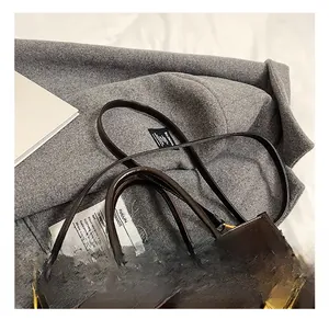 Makroaufnahme einer dunkelbraunen Kunstledertasche mit Goldbeschlägen und Kettenakzent