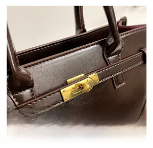 Detailaufnahme des goldenen Drehverschlusses und geprägtem dunkelbraunem Leder