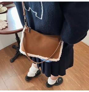 Close-up of caramel suede shoulder bag with faux shearling trim on a vintage interior background