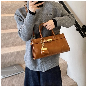 Braune Shopper-Tasche aus Kunstleder mit Goldbeschlägen auf einer modernen Treppe