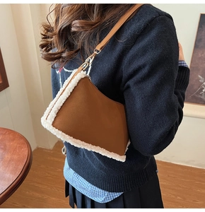 Detailed side view of brown faux suede bag with white lamb wool trim and gold hardware