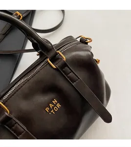Nahaufnahme der edlen dunkelbraunen Boston-Tasche aus Leder mit goldenen Metallbeschlägen