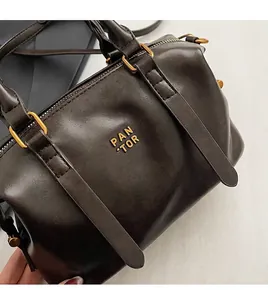 Detailansicht der dunkelbraunen Boston-Tasche mit goldenem PAN 'TOR-Logo und Reißverschluss