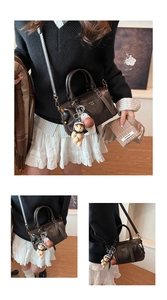 Detail einer dunkelbraunen Vintage-Boston-Tasche mit goldenen Beschlägen und Anhängern