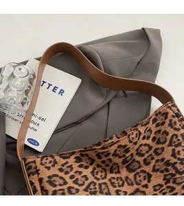 Detail of leopard print tote bag with brown leather shoulder straps on a grey fabric base