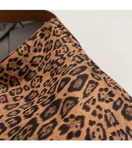 Detail of leopard print faux suede fabric texture and dark brown leather strap