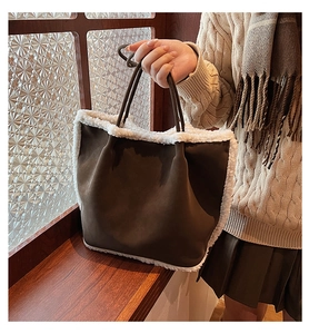 Detail of a brown suede tote bag with white faux shearling trim for autumn and winter