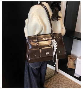Dark brown high-shine satchel with silver twist locks worn with a white fleece jacket
