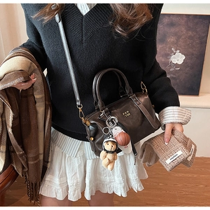 Detail of dark brown Boston bag with accessories and warm winter outfit styling