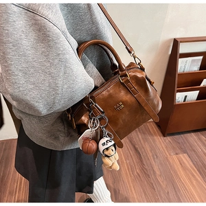 Detail of vintage brown Boston bag with shoulder strap and mini bear charm accents