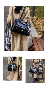 Detail of high-shine black tote bag with metal twist-lock pockets and fashion pendant