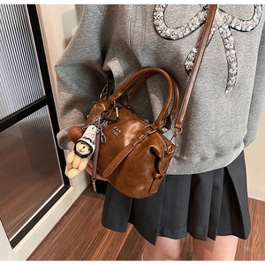 Close-up of vintage brown leather bag with teddy bear charm and PAN TOR metallic logo