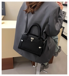 Détail du sac à main en cuir noir grainé avec fermoir métallique argenté et bandoulière