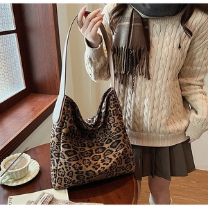 Detail shot of a large leopard print tote bag with suede texture on a female model