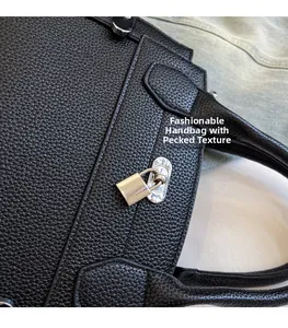 Close-up of black lychee grain leather handbag featuring a silver twist lock and padlock detail