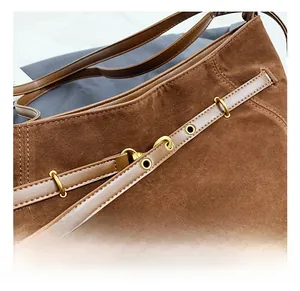 Detail of the high-quality gold hardware and brown suede texture on the tote bag