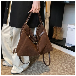 Detailed close-up of brown suede tote bag with leather handles and gold-tone metal hardware