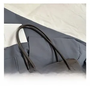 Detail of dark brown glossy leather handbag with slim dual handles and stitching