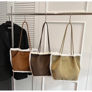 Three tote bags with suede texture and thick faux shearling trim on a hanging rack