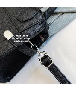 Detail of adjustable shoulder strap with silver buckle on black pebbled leather bag