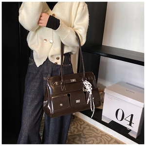 Detail of dark brown glossy PU leather bag with multi-pocket design and silver buckle