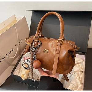 Nahaufnahme einer braunen Vintage Boston Handtasche mit Bärenanhänger in einer Box