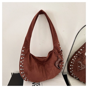 Détail d'un sac sous le bras en daim marron avec rivets argentés et charme cœur