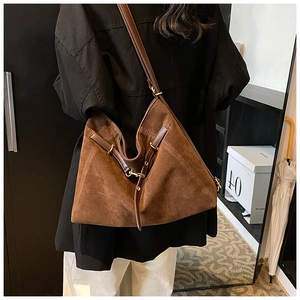 Detail of adjustable leather strap and golden hardware on a brown suede tote bag