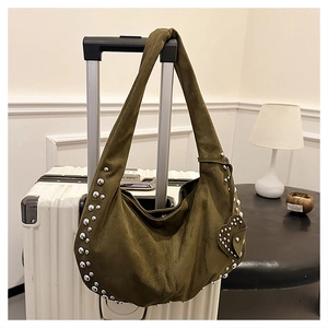 Détail du sac hobo vert olive avec rivets argentés et charme cœur sur un bagage