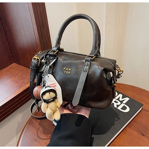 Detail of vintage brown leather Boston bag with gold logo and cute bear charm pendant