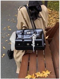 Outdoor view of a black vintage leather bag with pockets and silver hardware on a bench