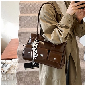 Detail view of a glossy dark brown leather satchel with functional flap pockets and buckles