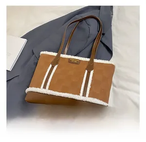 Macro detail of brown textured tote bag featuring white faux shearling trim and metal logo