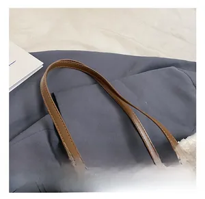 Close-up of brown textured leather tote bag with white faux fur trim and branded logo
