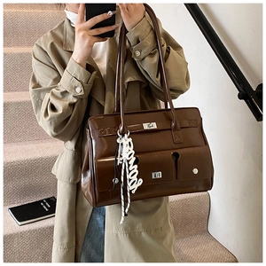 Vintage brown shoulder bag with multiple pockets and a metal turn-lock on a khaki coat model