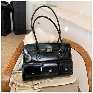Detail of black glossy messenger bag featuring dual front pockets and metallic turn-locks