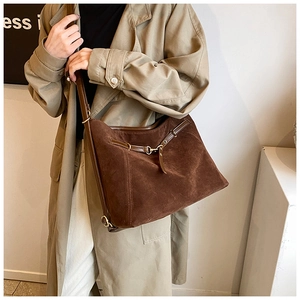 Detail of vintage brown suede tote bag with leather straps and gold metal hardware