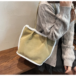 Close-up of suede shoulder bag featuring plush faux shearling trim and gold chain strap