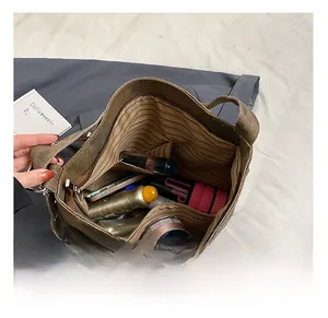 Detailed interior of a brown canvas tote bag showing striped lining and zipper pocket