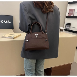 Detailed close-up of dark brown pebble leather tote bag with iconic flap and lock