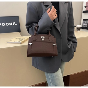 Detail view of dark brown lychee textured handbag with metallic lock on a model