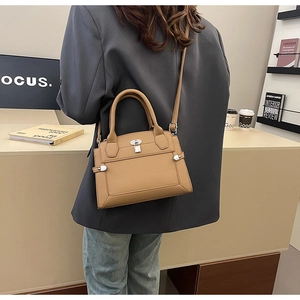 Detailed view of the tan pebbled leather handbag with adjustable strap and silver lock