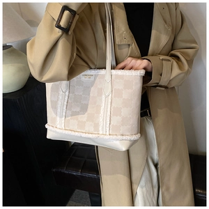 Detail of beige tote bag with floral patterns and white faux shearling trim on model
