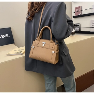 Litchi texture leather handbag in khaki shown with shoulder strap on a table