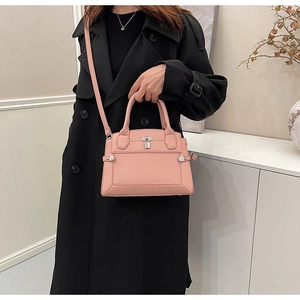 Close-up of pink litchi texture handbag with silver padlock and leather strap
